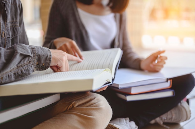 Éducation, apprentissage, étudiant, campus, université, concept de mode de vie. Deux étudiants sont assis par terre et lisent des livres pour l'éducation. Étude pour la préparation aux tests à l'université.