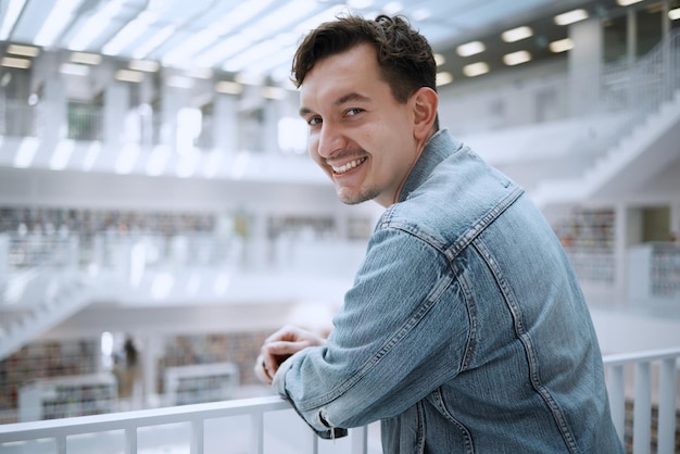 Éducation collégiale et portrait d'un homme dans la bibliothèque pour apprendre la recherche et la lecture Sourire les objectifs futurs et étudiant heureux à l'université pour étudier les connaissances et les bourses d'études pour l'école