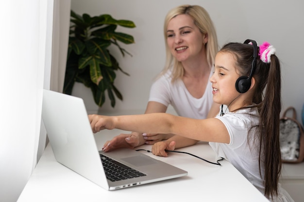 Éducation en ligne des enfants. Mère et fille d'âge préscolaire regardant une leçon vidéo par téléphone à la maison.