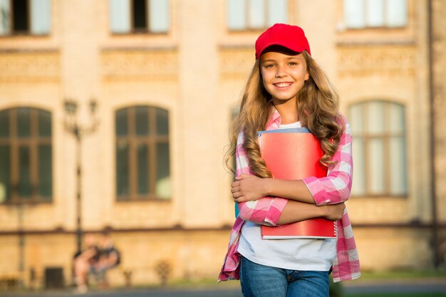 Éducation non formelle Un enfant heureux tient des livres dans la cour de l'école Bibliothèque scolaire Apprentissage non formel