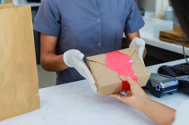 Photo dueno de tienda que trabaja con guantes quirurgica dando comida para llevar a los clientes