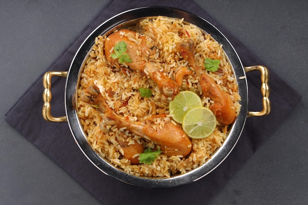 Dum poulet biriyani, image en gros plan du Kerala-Thalassery biriyani qui est mélangé avec du masala et de couleur jaune disposé dans un bol de service en cuivre et garni de tranches de citron placées sur du graphite