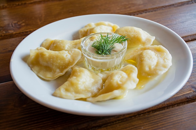 Dumplings sur une assiette blanche avec de la crème sure. -