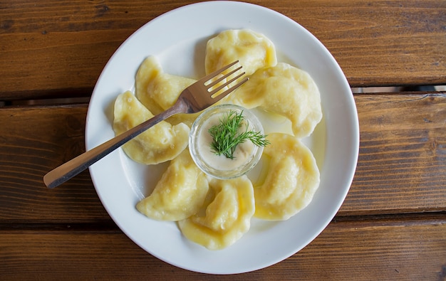 Dumplings sur une assiette blanche avec de la crème sure. -