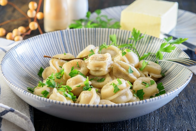 Photo dumplings bouillis frais faits maison dans le bol bleu moderne avec des épices, du sel et du beurre sur le bois