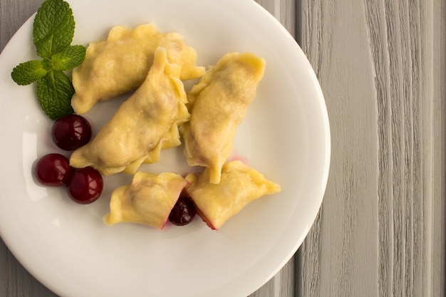 Dumplings à la cerise dans la plaque blanche sur la table en bois gris.Vue de dessus.Copier l'espace.