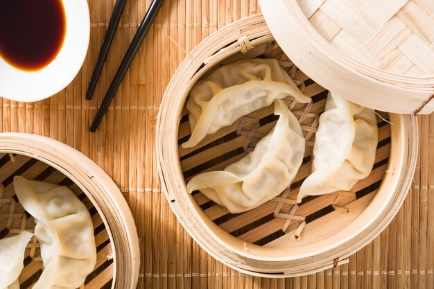 Dumplings ou gyoza servis dans un steamer traditionnel et de la sauce soja sur une natte de bambou