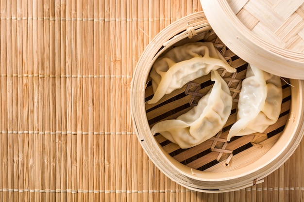 Dumplings ou gyoza servis dans de la vapeur traditionnelle et de la sauce soja sur un espace de copie en natte de bambou