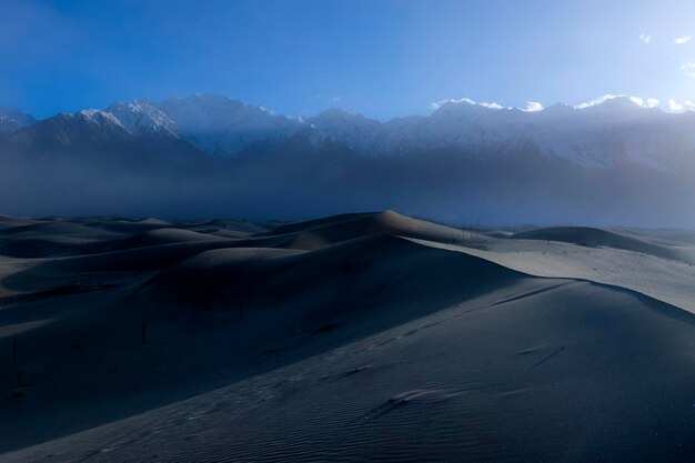 Une dune de sable avec une montagne en arrière-plan