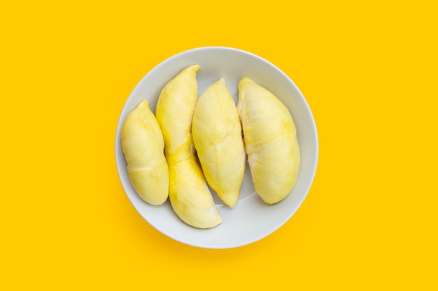 Durian coupé mûr en plaque blanche sur fond jaune.