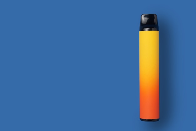 E-cigarette jetable en dégradé de couleur jaune sur fond bleu isolé. Le concept de tabagisme moderne, de vapotage et de nicotine. Vue de dessus