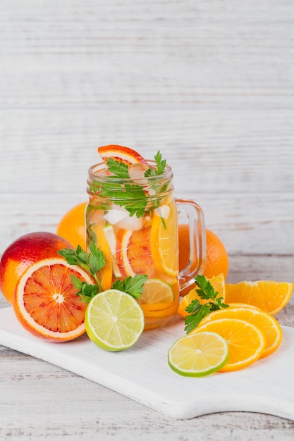 Eau d'agrumes et d'herbes pour la désintoxication ou un régime dans des bouteilles en verre sur planche de bois