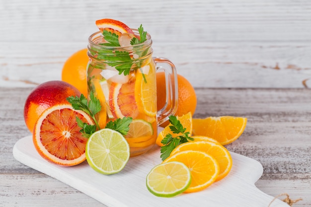 Eau d'agrumes et d'herbes pour la désintoxication ou un régime dans des bouteilles en verre sur planche de bois