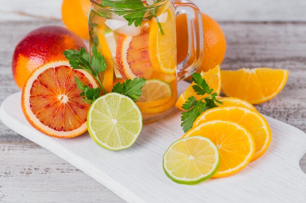 Eau d'agrumes et d'herbes pour la désintoxication ou un régime dans des bouteilles en verre sur planche de bois