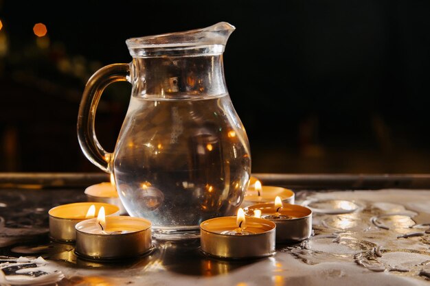 L'eau bénite est chauffée par des bougies sur un piédestal dans une église pour le rite de baptême d'un enfant