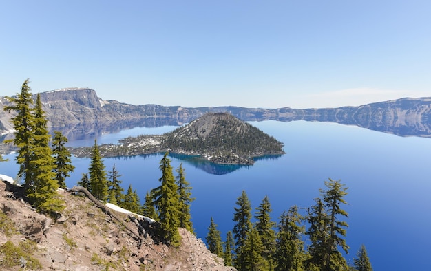 Eau bleue claire du parc national du lac Crater dans l'Oregon au début du printemps avec un peu de neige laissée par l'île d'hiver Wizard au loin