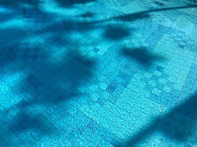 Une eau bleue avec une ombre du mot piscine dessus.