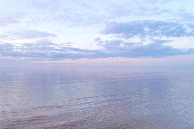 Eau calme à la surface de la mer. Nuages colorés au coucher du soleil. Soirée chaude sur la plage. Ambiance estivale. Vue sur le paysage.