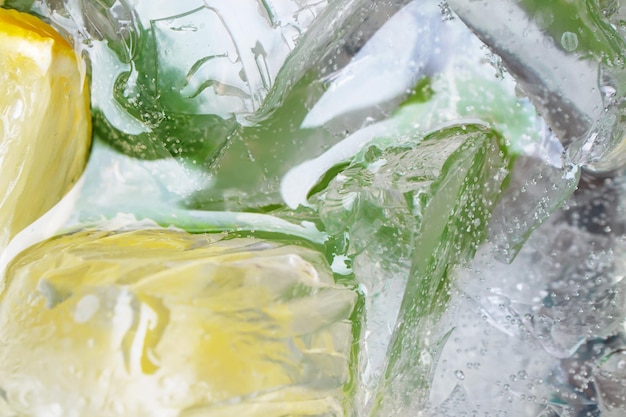 Eau avec citrons feuilles de menthe et glaçons en verre gros plan