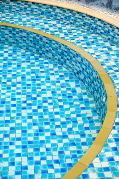 L'eau claire dans une petite piscine encore avec des carreaux bleus et blancs