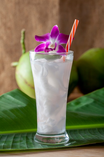 Eau de coco fraîche dans un verre sur une planche de bois à boire