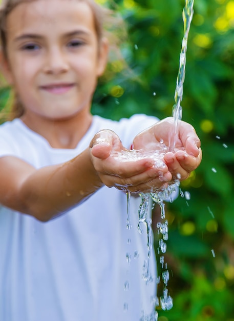 Photo l'eau coule dans les mains de l'enfant. mise au point sélective. la nature.