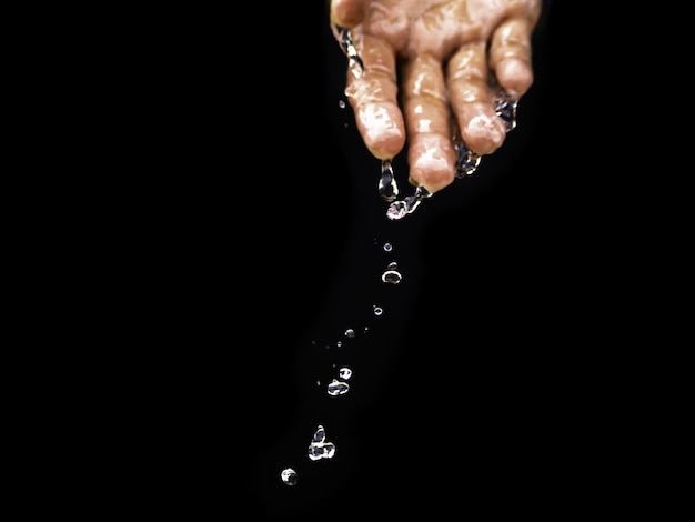 L'eau coule sur la paume de la main en bas. La pureté de l'eau. Les bienfaits de l'eau.