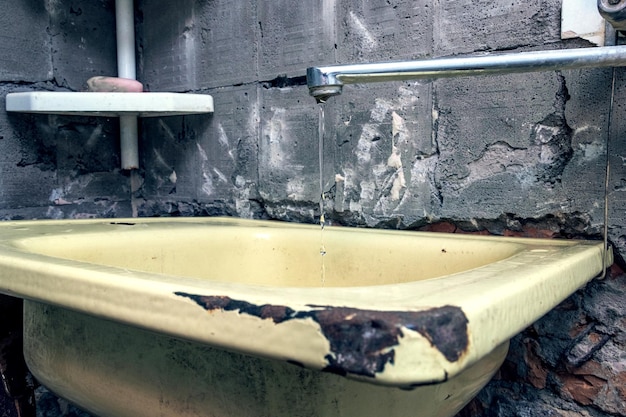 L'eau coule d'un robinet dans une ancienne cuisine abandonnée Un robinet d'eau endommagé dans les bidonvilles