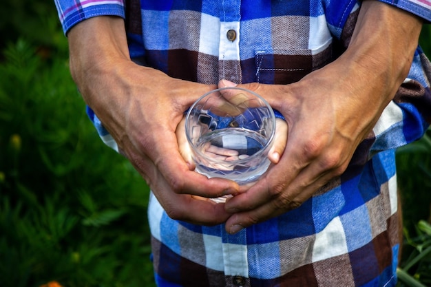 De l'eau dans un verre entre les mains d'un enfant et d'un père. La nature.