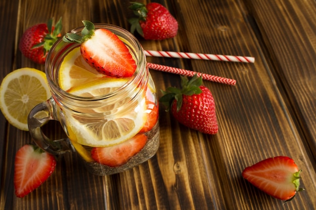 Eau de désintoxication avec chia, fraise et citron sur table en bois