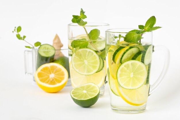 Eau détox au citron lime concombre gingembre et menthe et ingrédients pour sa préparation. Aliments sains riches en vitamines et antioxydants