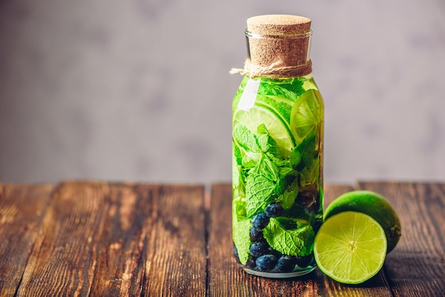 Eau détox en bouteille avec espace de copie de menthe citron vert et myrtille sur la gauche