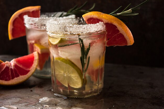 Photo eau détox infusée de pamplemousse et de romarin dans une bouteille en verre sur une table en bois gris. alimentation saine alimentation et concept de perte de poids, espace copie pour le texte