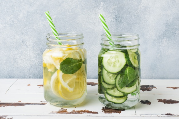 Eau douce dans un bocal avec citron, concombre et menthe sur une table en bois.