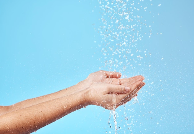 Eau de douche et mains d'une femme nettoyant, économisant et récupérant du liquide sur fond de studio bleu