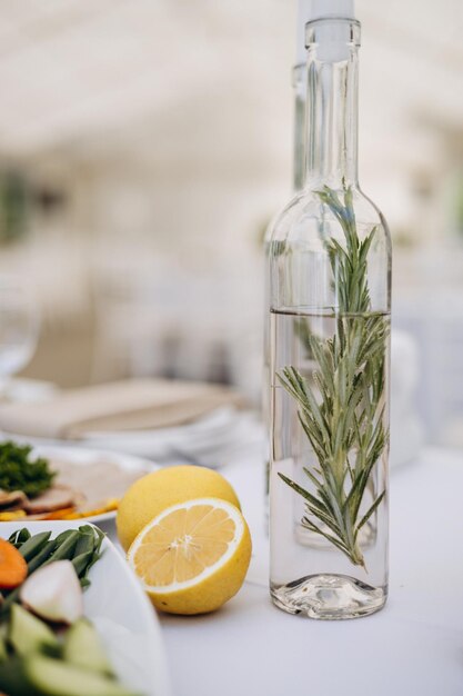 Photo de l'eau avec des herbes dans une bouteille et du citron à côté