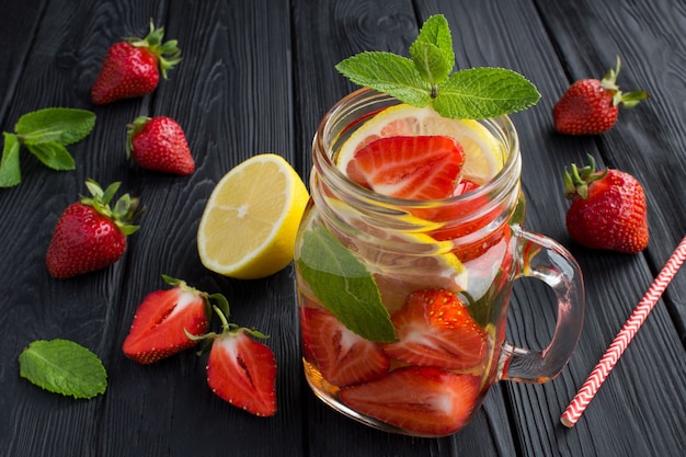 Eau infusée à la fraise et au citron dans le verre sur la table noire