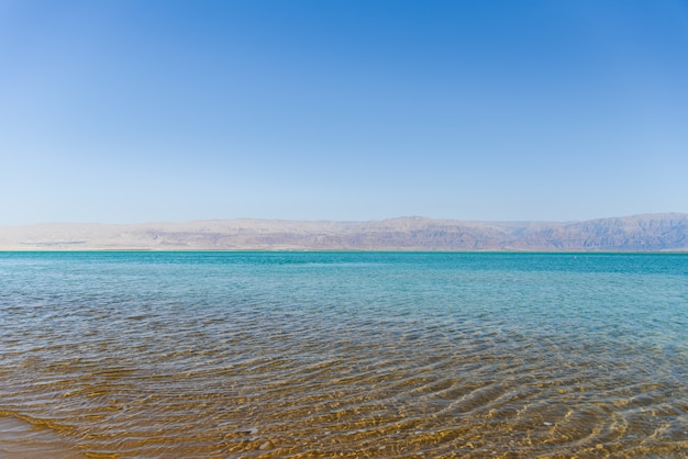 Une eau limpide et cristalline dans la mer lors d’une journée ensoleillée avec des montagnes à Côte de la mer morte.