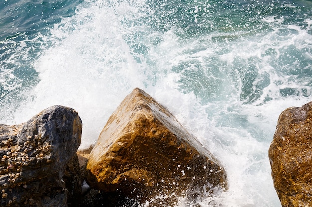 L'eau de mer bat contre les rochers et fait des vagues avec de la mousse, une jetée accidentée dans la mer