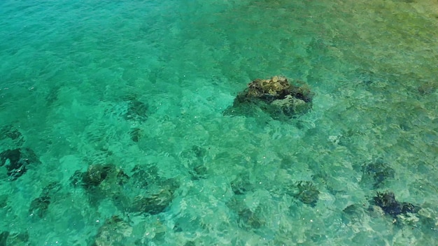 Eau de mer calme près des pierres. Eau de mer bleue paisible et rochers gris dans un endroit parfait pour la plongée en apnée sur l'île de Koh Tao par une journée ensoleillée en Thaïlande. Texture de fond naturel.