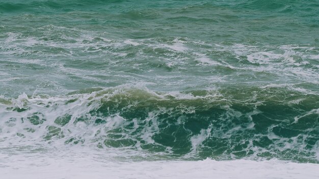 L'eau de la mer, l'océan, les grandes vagues, les éclaboussures sur la plage, l'eau de mer, les grandes ondulations qui se heurtent au rivage.