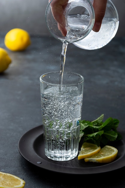 Eau pétillante dans le verre, verser de l'eau dans le verre. Fond gris