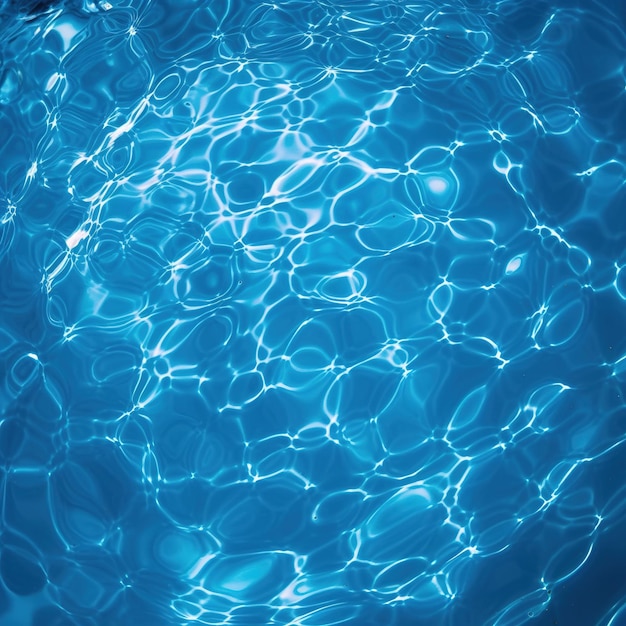 L'eau de la piscine est bleue et le soleil brille sur l'eau