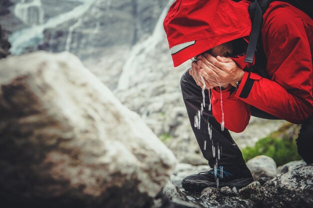 Eau potable dans la nature Randonneur caucasien buvant de l'eau douce directement de la rivière de montagne