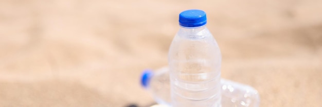 Eau potable froide dans des bouteilles transparentes sur la mer de plage de sable