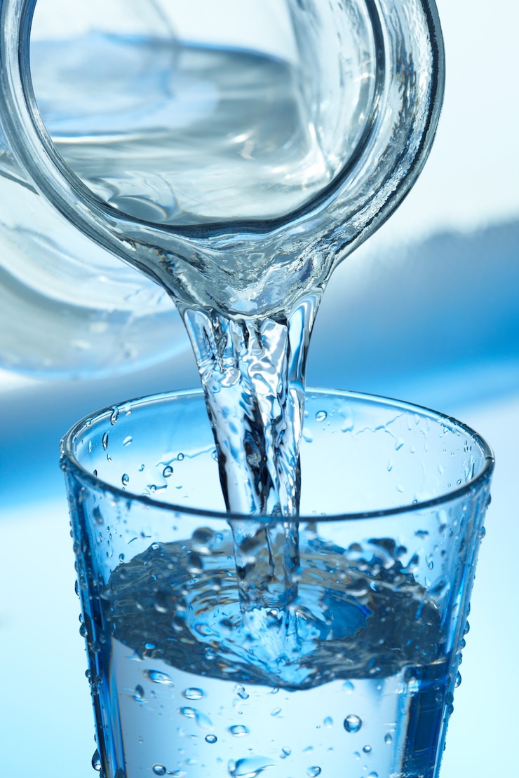 Photo l'eau qui coule d'une cruche dans un verre sur bleu.