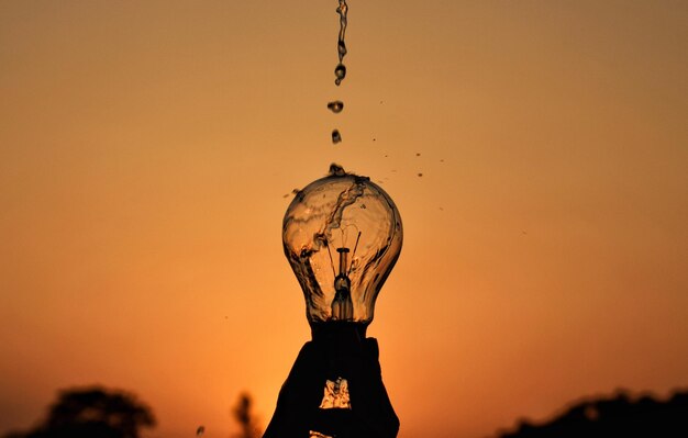 Photo l'eau qui tombe sur l'ampoule contre un ciel orange clair