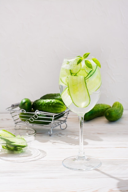 Eau rafraîchissante avec des tranches de concombre et de feuilles de basilic dans un verre