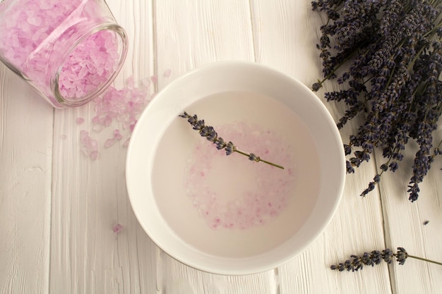 Eau salée de lavande et fleurs sur la vue de dessus de fond en bois blanc