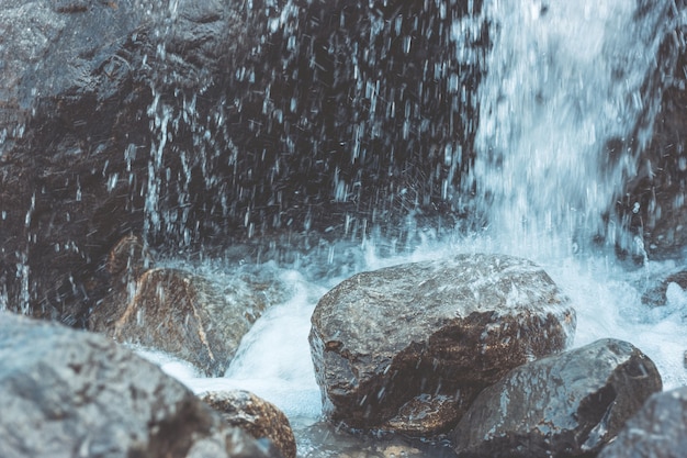 L'eau tombe sur les pierres et les rochers. Éclaboussures, pluie, humidité. Filmé de près.